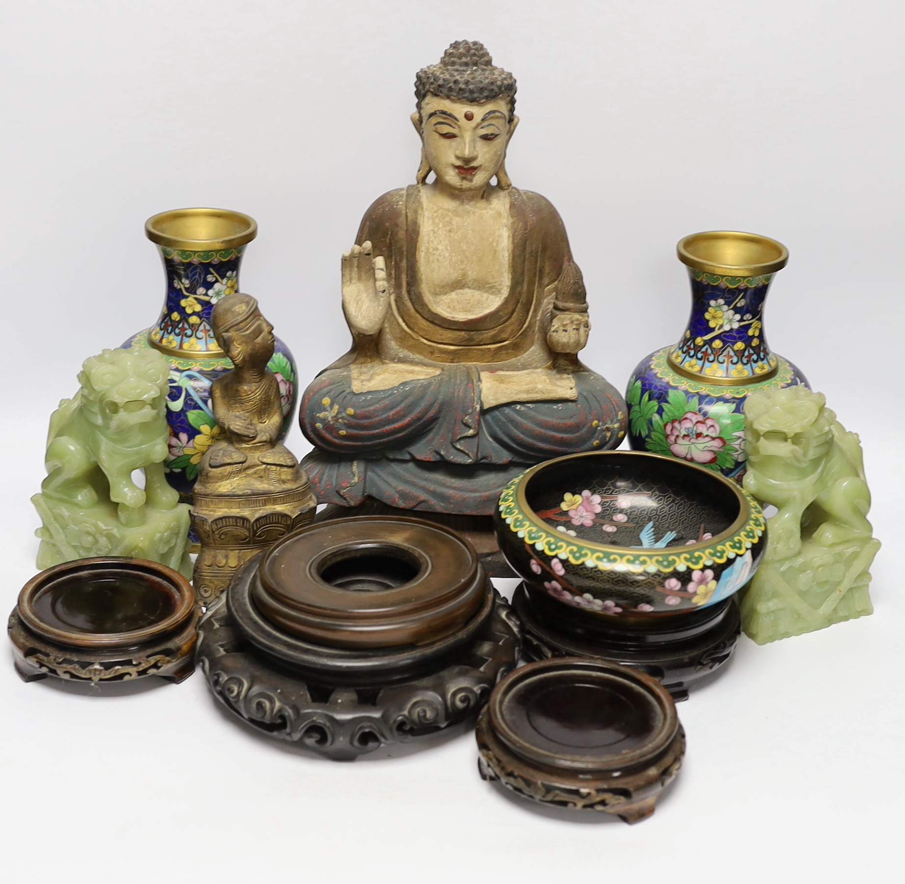 A pair of Chinese cloisonné enamel vases and a bowl on stand, two soap stone lion dogs, a carved and painted Buddha, a deity and four wooden stands, Buddha 33cm high